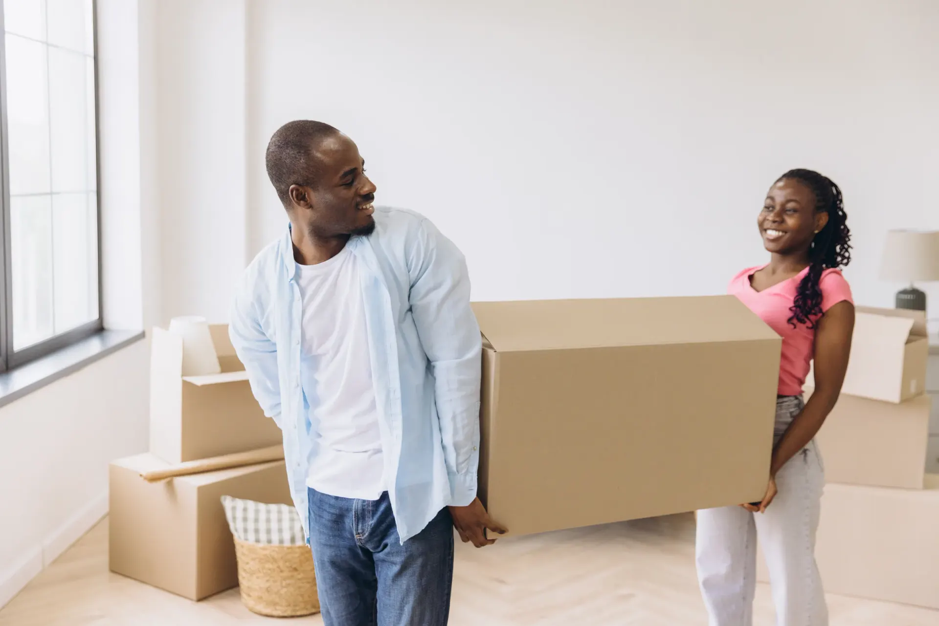 Un couple transporte un carton dans son nouveau logement